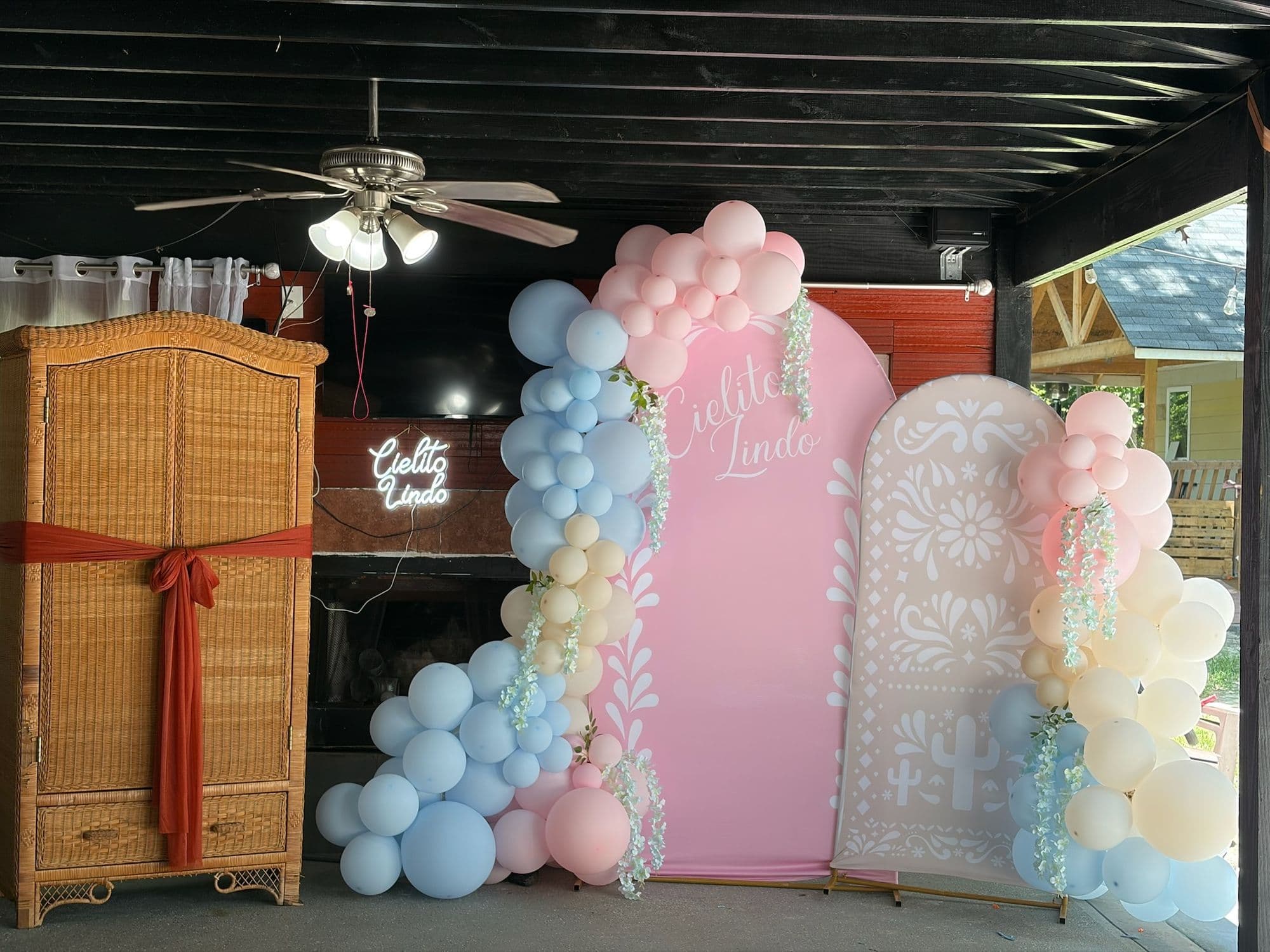 Ropero de mimbre atado con un moño terracota junto al fondo de globos