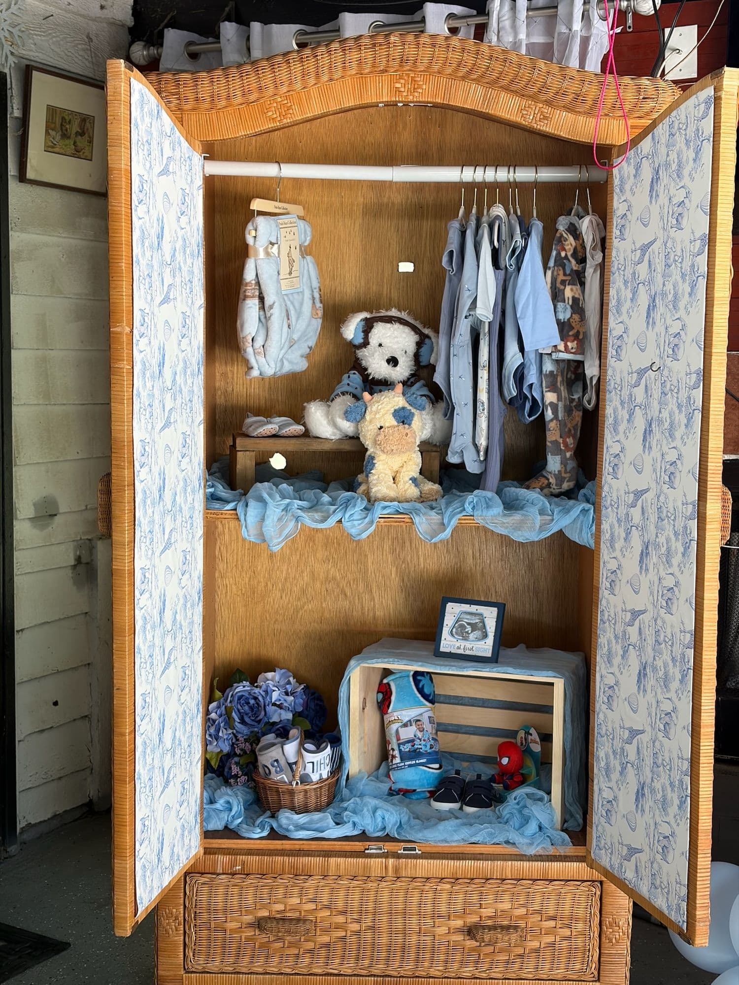 Ropero abierto decorado con ropa de bebé, un oso de peluche y recuerdos