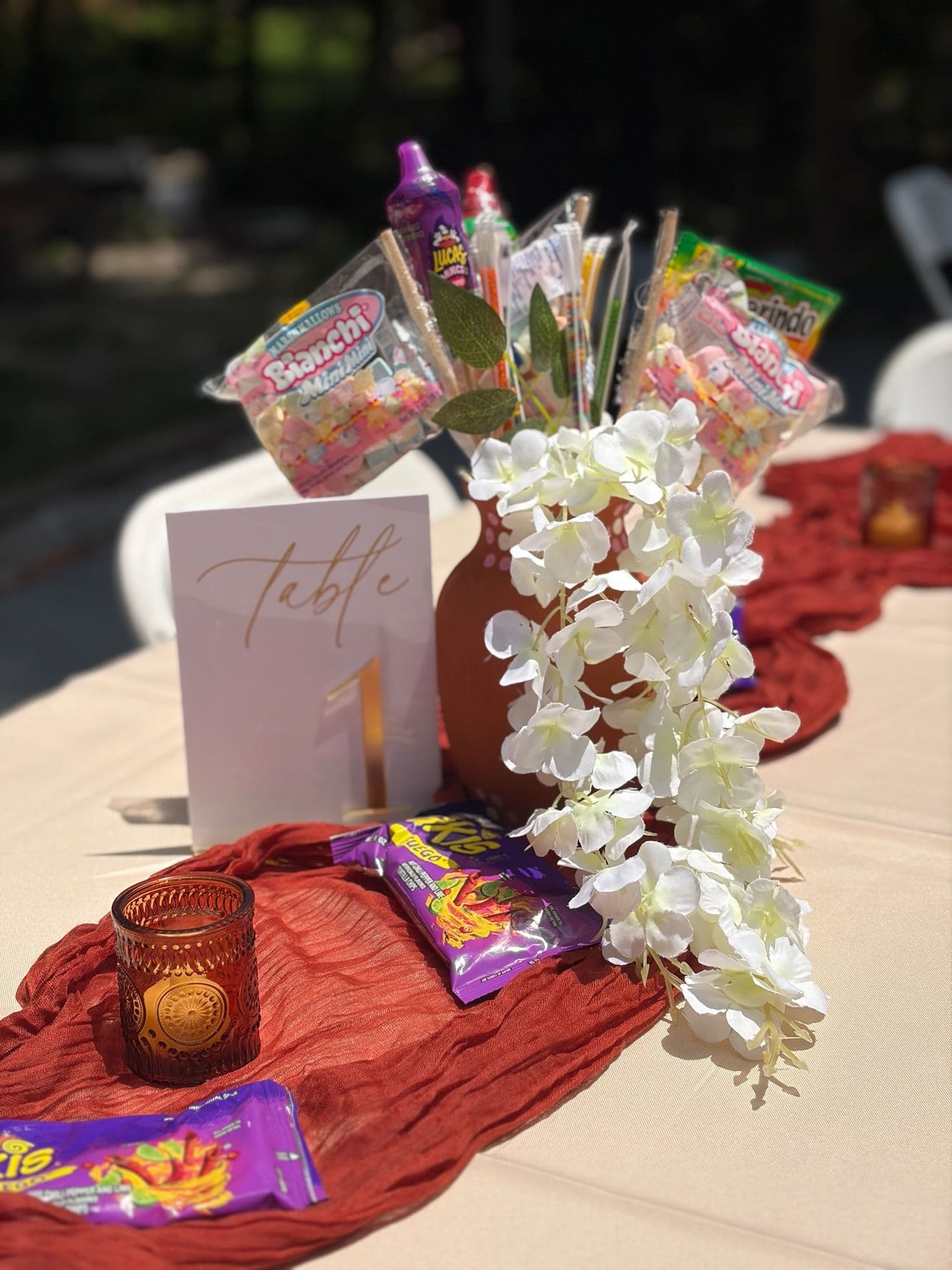 Centro de mesa con dulces mexicanos, orquídeas blancas y camino terracota