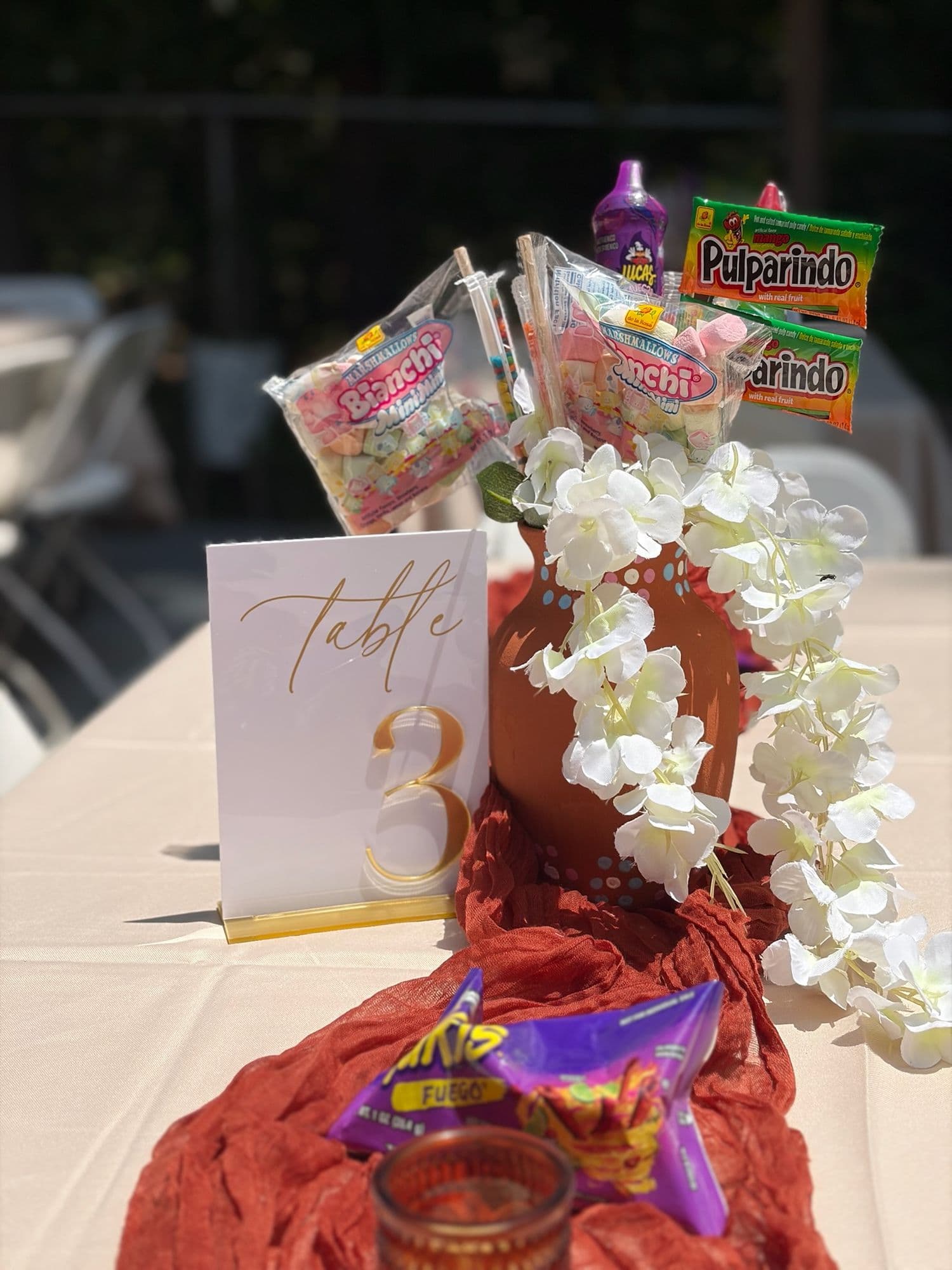 Centro de la mesa tres con dulces mexicanos y orquídeas en cascada