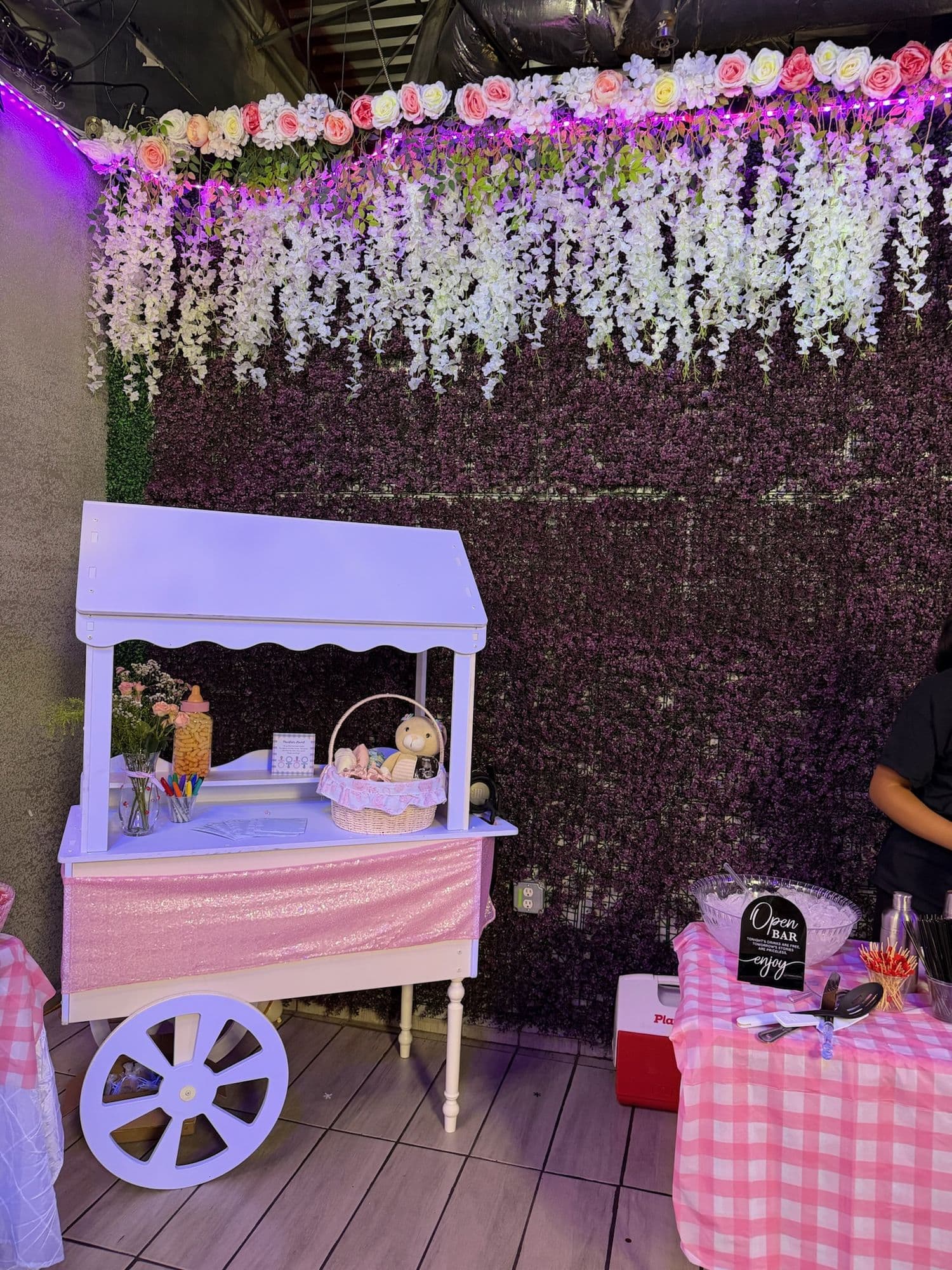 Carrito de dulces frente a un muro de glicinas colgantes