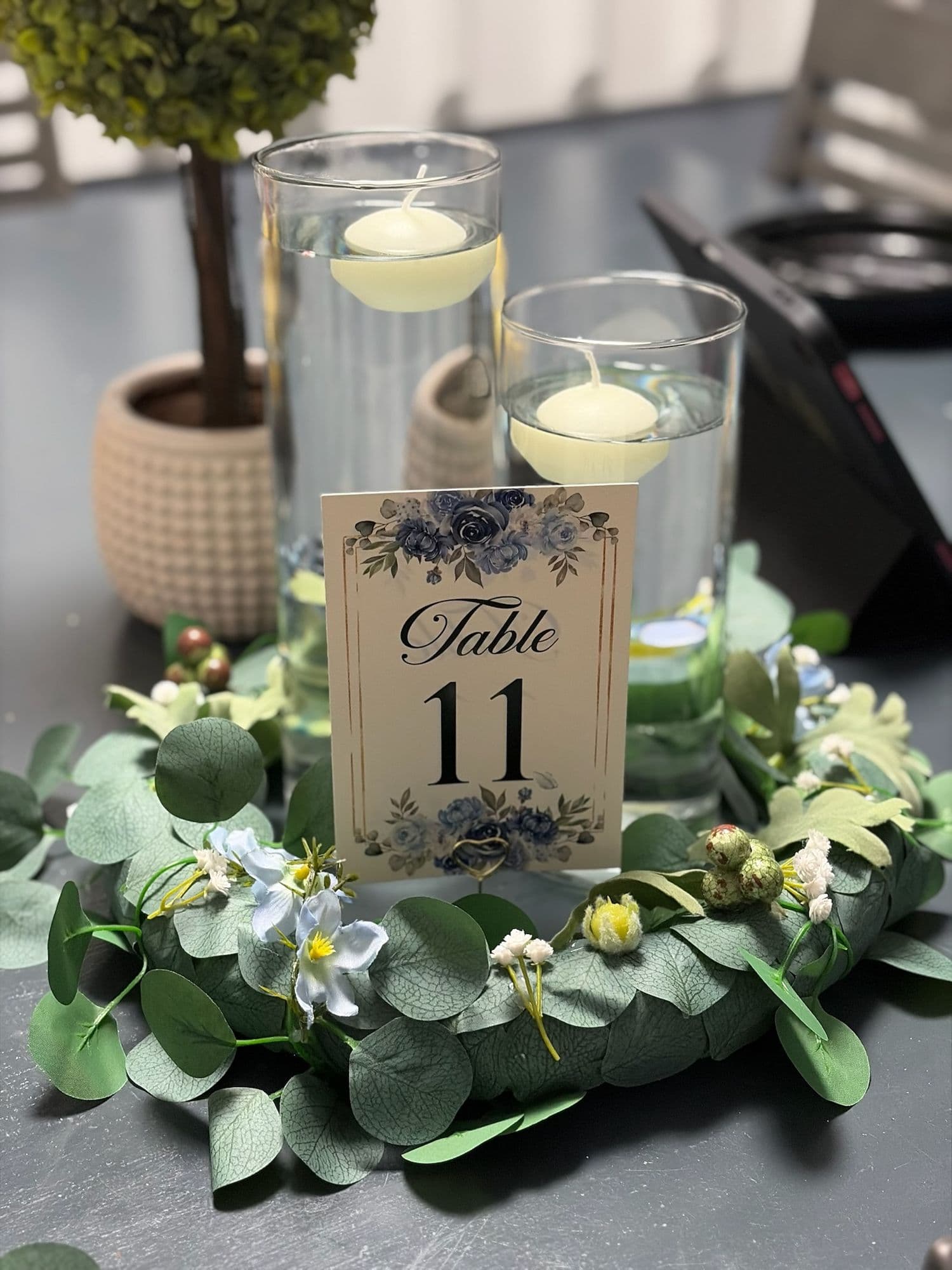 Número de mesa floral con velas flotantes y una corona de eucalipto