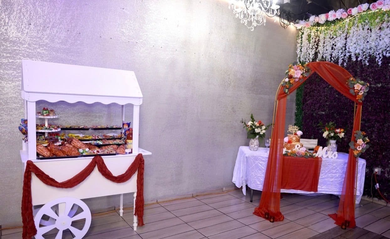 White dessert cart with a terracotta swag beside the sweetheart arch