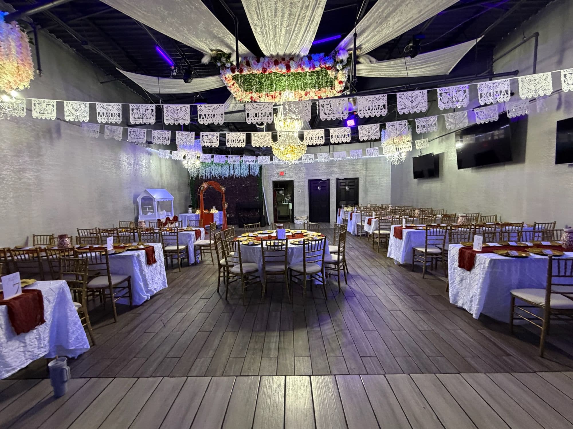 Wide view of the reception with papel picado overhead and round guest tables