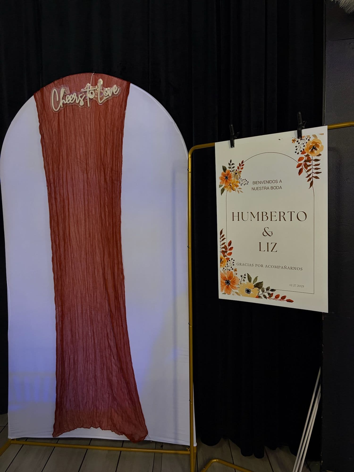 Terracotta-draped arch panel beside a floral welcome sign