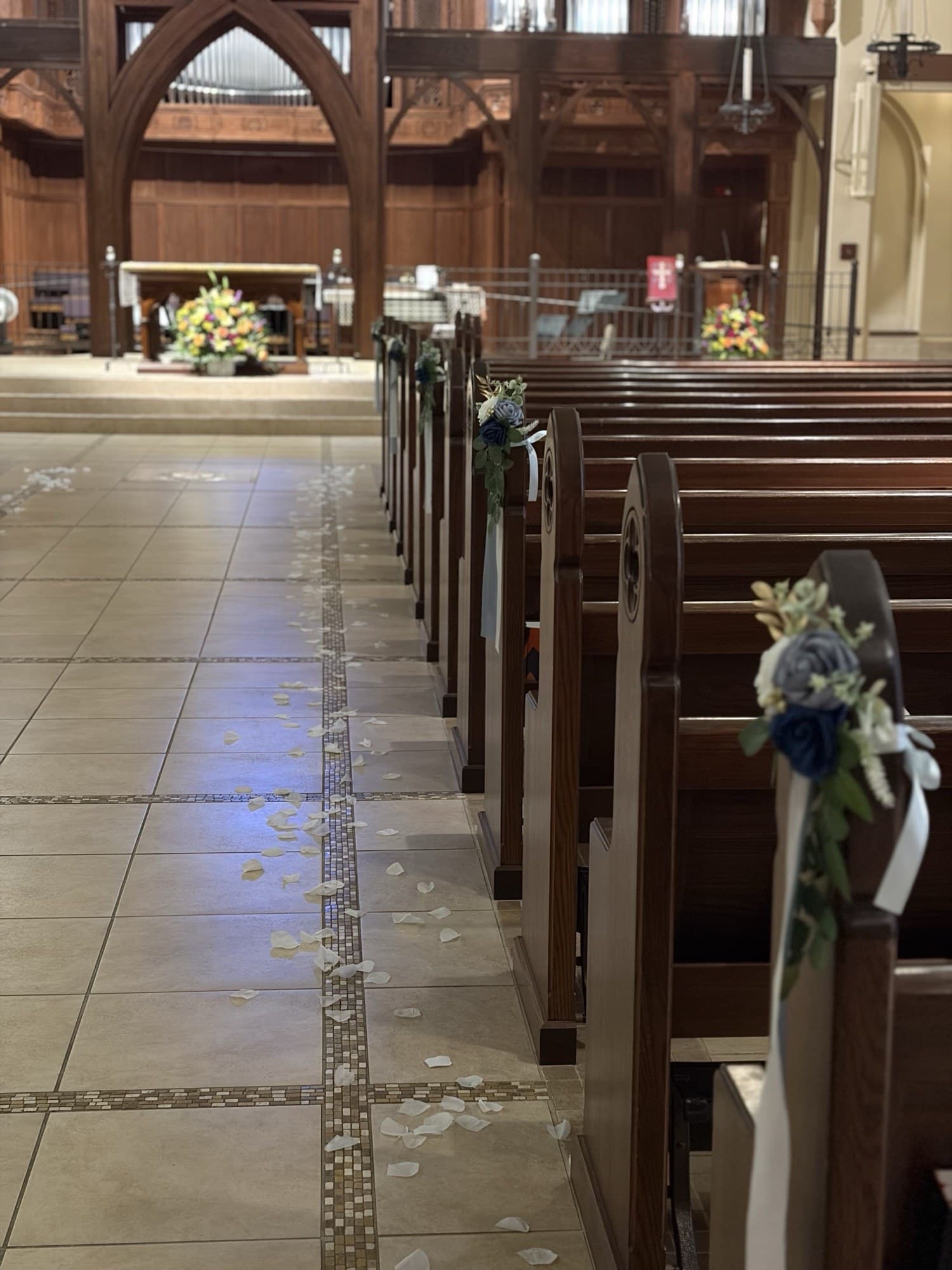 Church aisle lined with pew florals and scattered petals