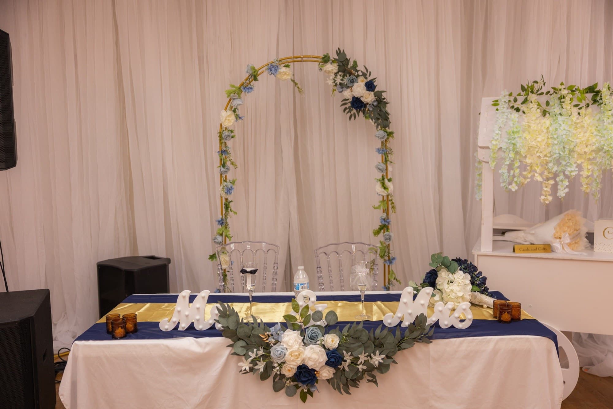 Sweetheart table with a floral arch, Mr & Mrs sign, and gold runner