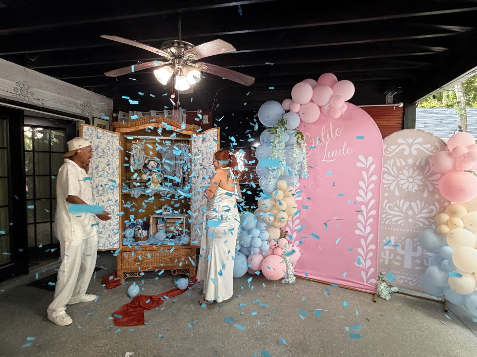 Los futuros papás en el momento de la revelación con confeti azul en el aire