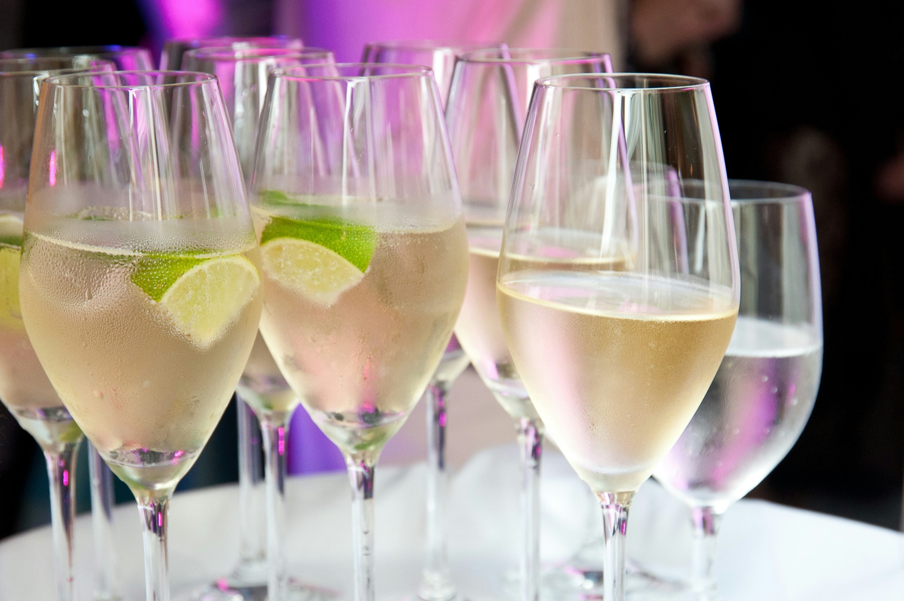 Glasses of sparkling wine garnished with lime, served at an open bar