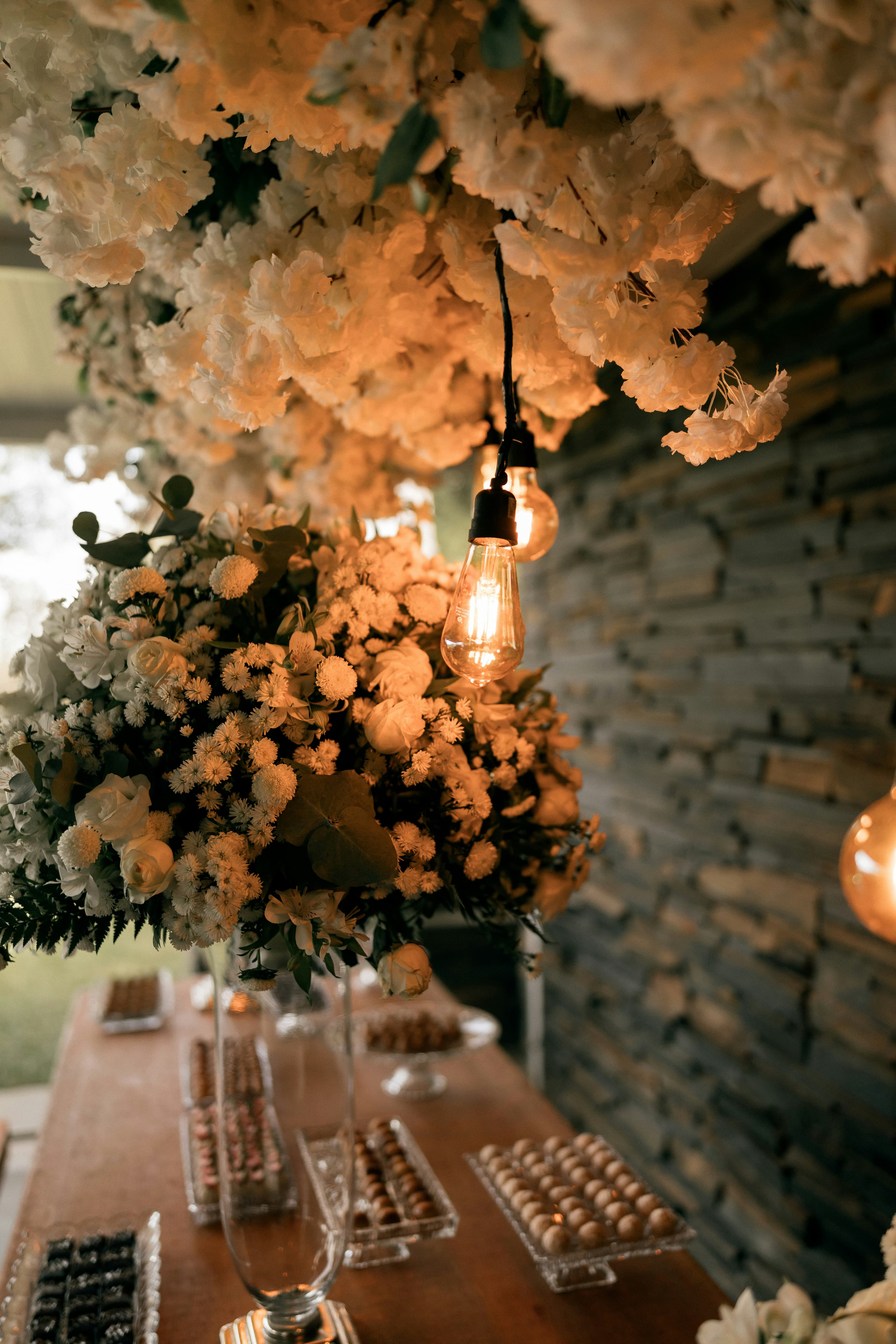 Abundantes flores blancas y cálida iluminación sobre una mesa de postres decorada