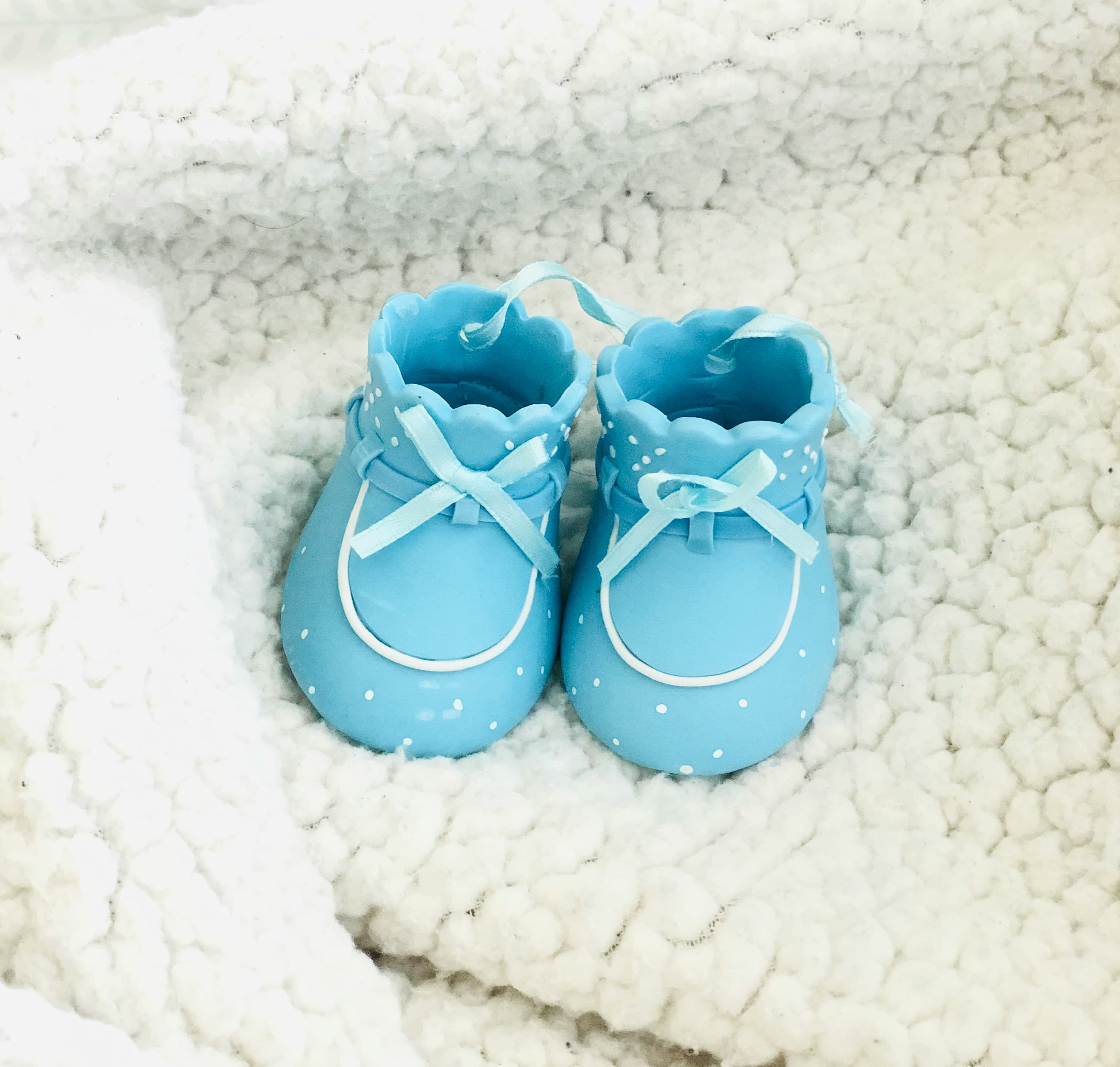 Tiny blue baby shoes resting on a soft blanket for a gender reveal
